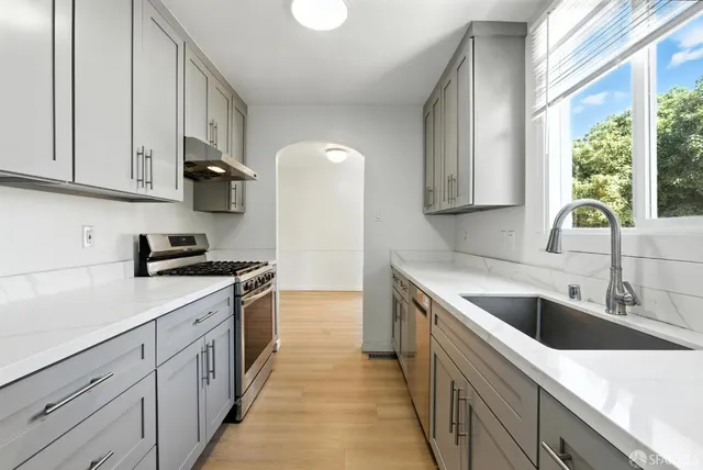 a kitchen with granite countertop a sink dishwasher stove and cabinets