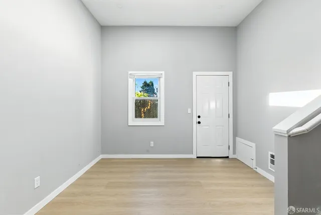 a view of an empty room with window and wooden floor