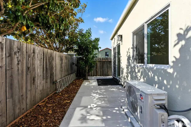 a view of a pathway of a house with a small yard and wooden fence