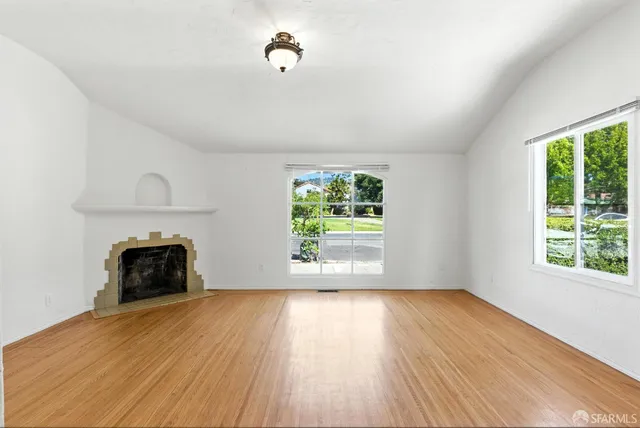 wooden floor fireplace and windows in an empty room