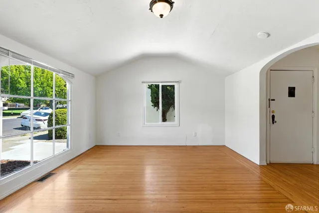 a view of an empty room with wooden floor and a window