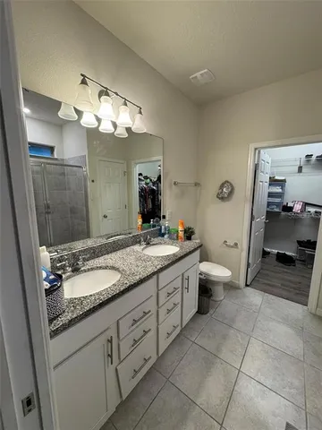 a spacious bathroom with a granite countertop sink a toilet and a mirror