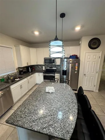 a kitchen with kitchen island granite countertop a counter space dining table and a chandelier