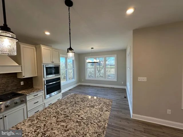 a kitchen with stainless steel appliances granite countertop a refrigerator a stove and a wooden floors