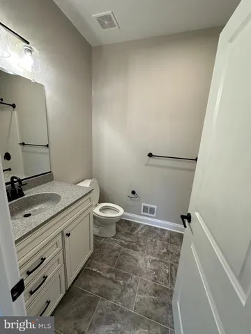 a bathroom with a granite countertop sink a toilet and a mirror