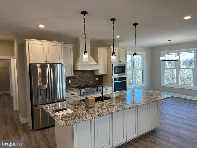 a kitchen with stainless steel appliances granite countertop a sink a refrigerator a stove and a wooden floors