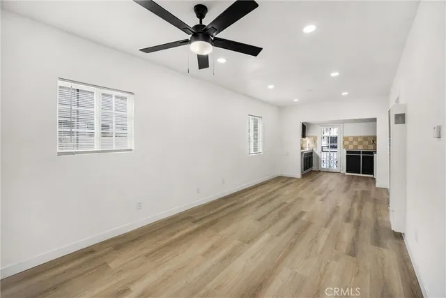 a view of empty room with wooden floor and fan