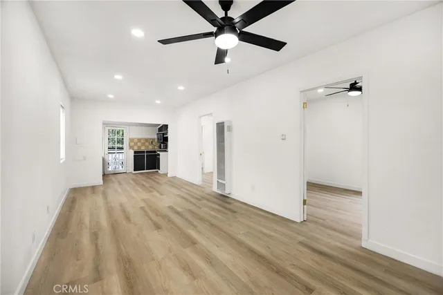 a view of empty room with wooden floor and ceiling fan