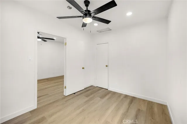 an empty room with wooden floor ceiling fan and carpet