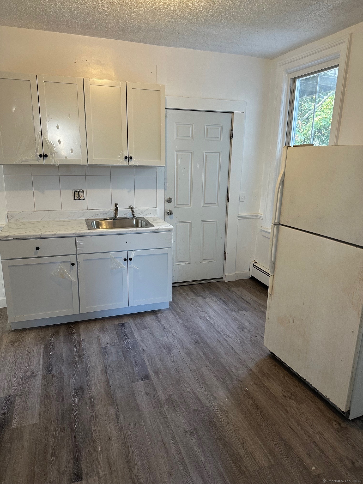 23 Ward Street, Unit 2 Vernon, CT 06066 - Photo 2 of 9 a kitchen with wooden floors and white cabinets