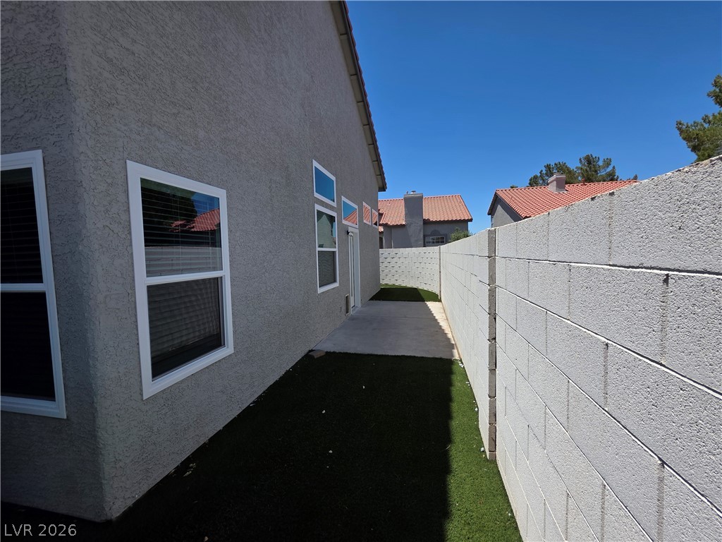 2275 Ramsgate Drive Henderson, NV 89074 - Photo 12 of 84 A well-maintained side yard with artificial turf and a privacy wall offers a tranquil outdoor retreat.