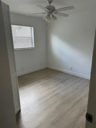 an empty room with a window and a ceiling fan