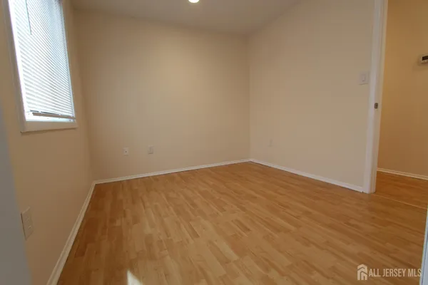 an empty room with wooden floor closet and windows