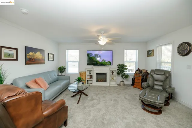 a living room with furniture a fireplace a flat screen tv and a large window