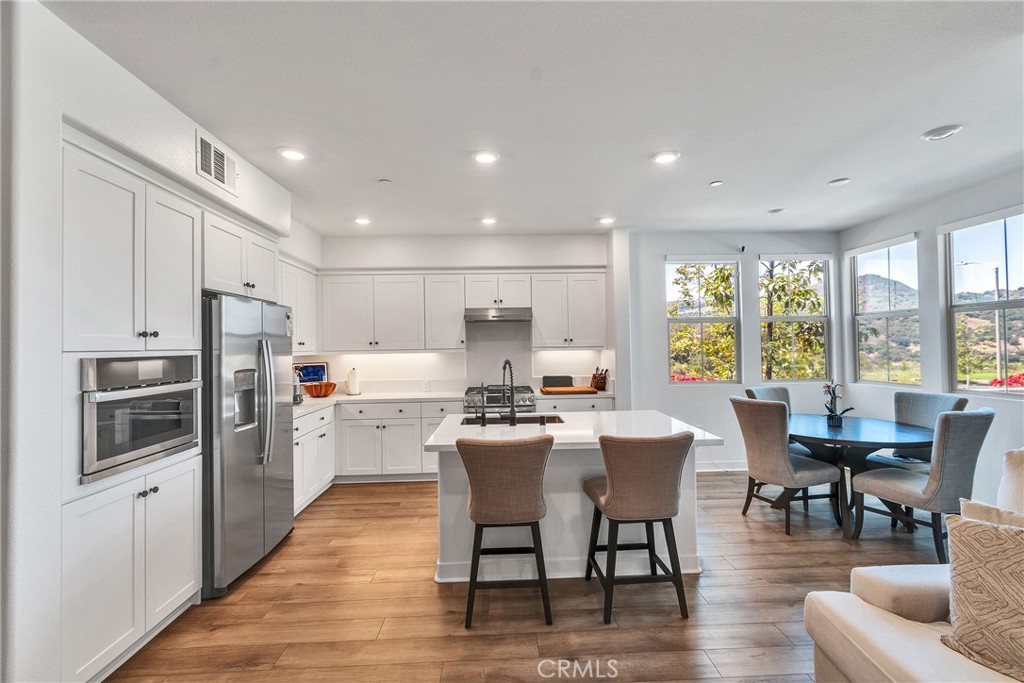 1200 Lasso Way, Unit 105 Rancho Mission Viejo, CA 92694 - Photo 4 of 43 a kitchen with a dining table wooden floor and stainless steel appliances