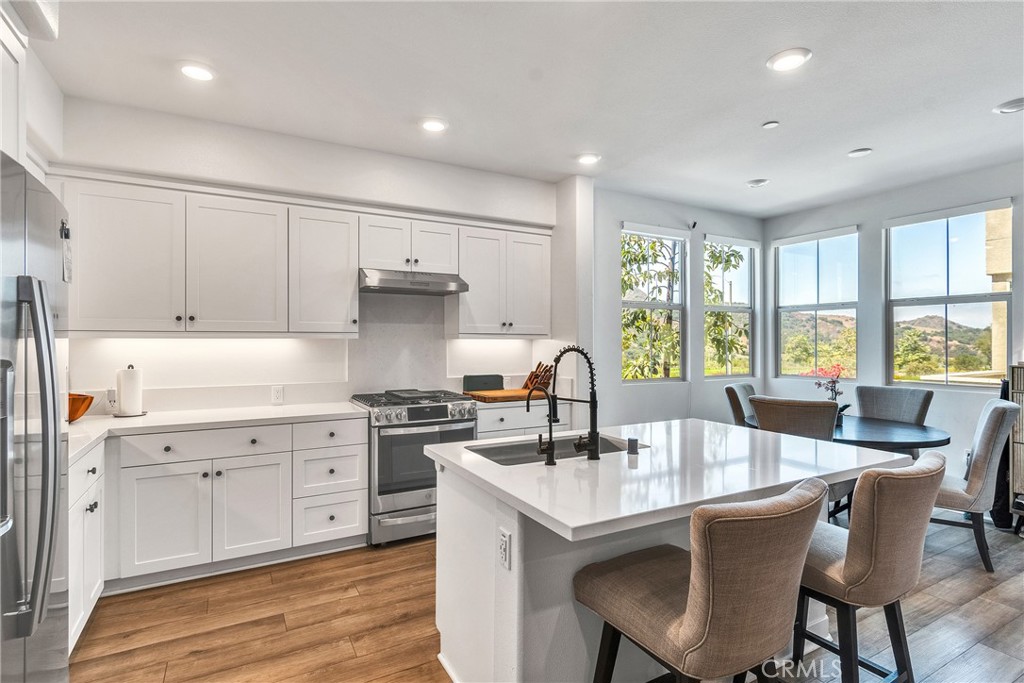 1200 Lasso Way, Unit 105 Rancho Mission Viejo, CA 92694 - Photo 5 of 43 a kitchen with a stove a sink a table and chairs