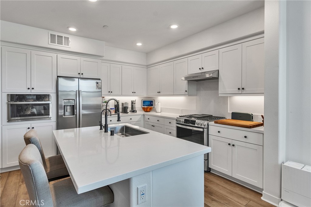 1200 Lasso Way, Unit 105 Rancho Mission Viejo, CA 92694 - Photo 6 of 43 a kitchen with kitchen island a stove a sink a refrigerator a dining table and chairs