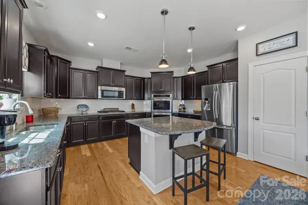 a kitchen with stainless steel appliances granite countertop a sink stove and refrigerator