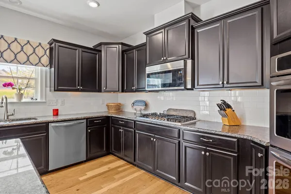 a kitchen with stainless steel appliances granite countertop a sink dishwasher and cabinets with wooden floor