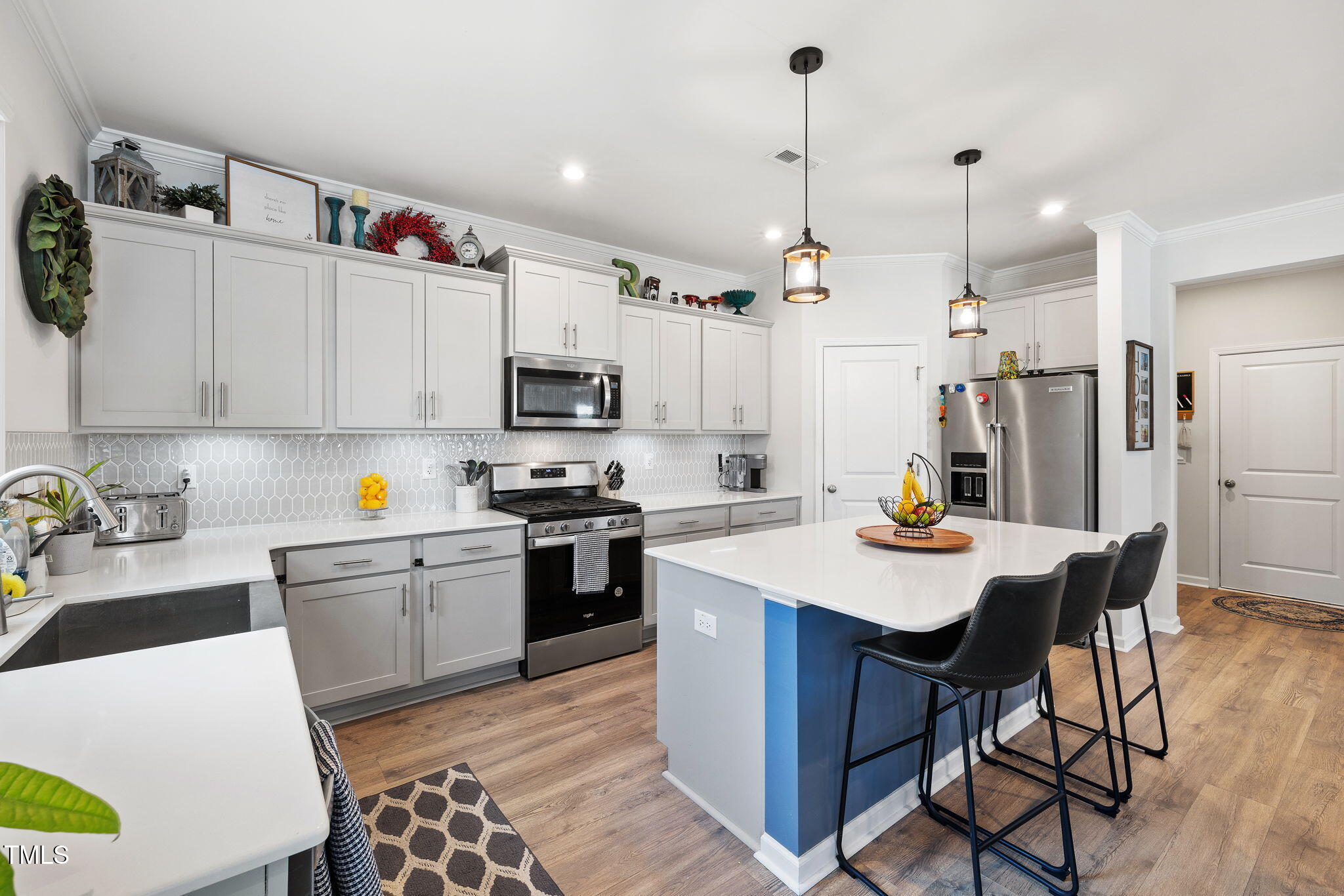 95 Madden Rose Loop Garner, NC 27529 - Photo 20 of 51 a kitchen with a sink a stove a kitchen island with chairs cabinets and stainless steel appliances
