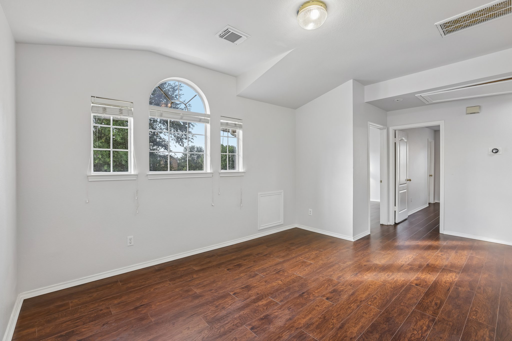 1721 Long Rifle Drive Austin, TX 78754 - Photo 20 of 38 Rich hardwood-style flooring extends across this bright, versatile room, featuring an elegant arched window.
