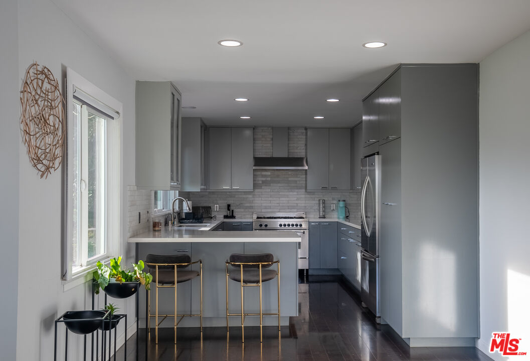 1438 Davies Drive Beverly Hills, CA 90210 - Photo 3 of 16 a kitchen with stainless steel appliances granite countertop a sink a stove a refrigerator and a dining table with wooden floor
