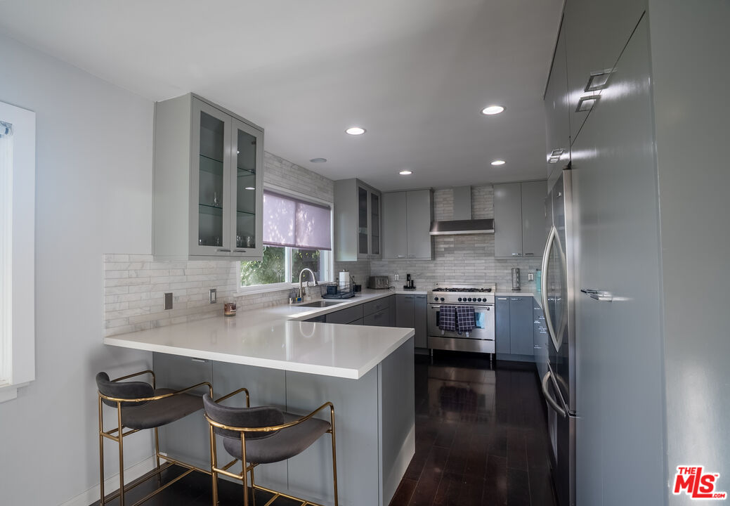1438 Davies Drive Beverly Hills, CA 90210 - Photo 4 of 16 a kitchen with a sink stools a counter space and cabinets