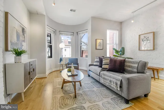 a kitchen with stainless steel appliances granite countertop a refrigerator a stove a sink a dining table and chairs with wooden floor