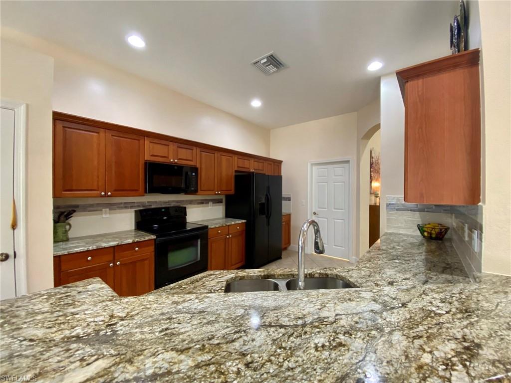 7806 Founders Circle Naples, FL 34104 - Photo 7 of 28 a kitchen with stainless steel appliances kitchen island granite countertop a refrigerator and a sink
