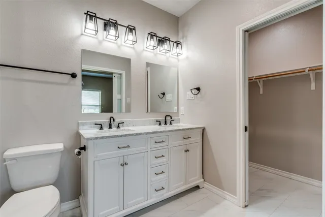 a bathroom with a granite countertop sink toilet a mirror a vanity and shower