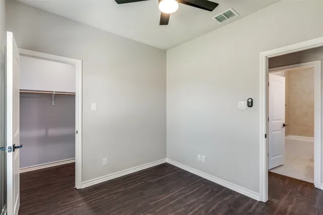 an empty room with wooden floor chandelier fan and closet