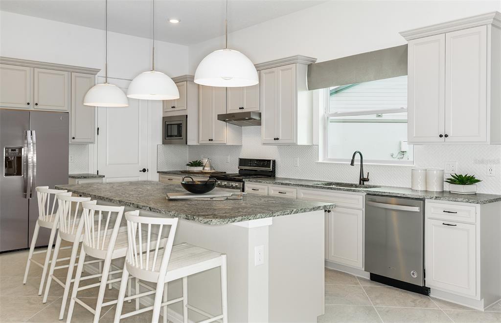 1947 Spring Shower Circle Kissimmee, FL 34744 - Photo 4 of 18 a kitchen with stainless steel appliances granite countertop a sink a stove a dining table and chairs