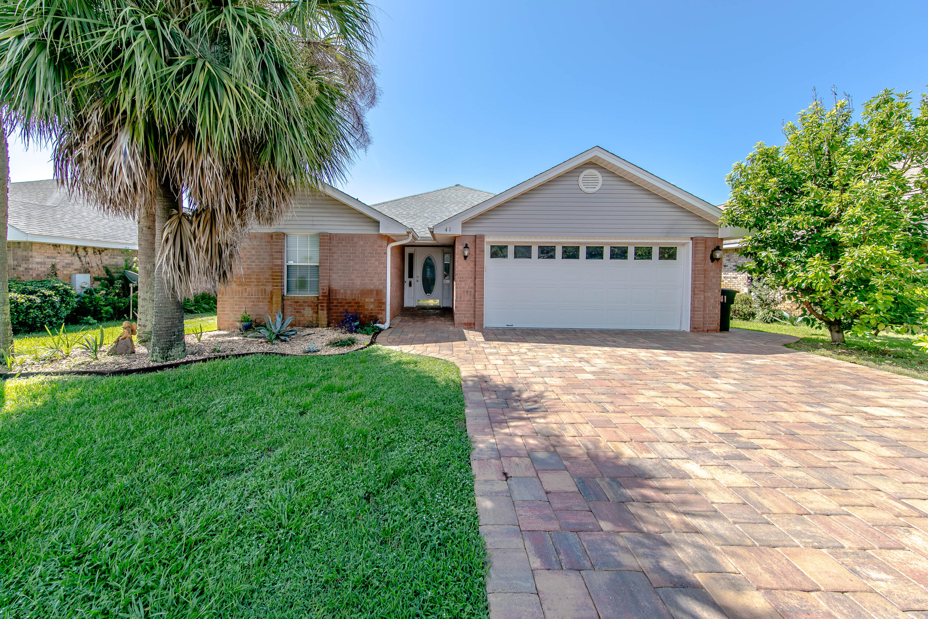 a view of a house with a yard and palm trees