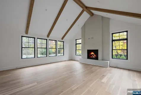 an empty room with windows fireplace and wooden floor