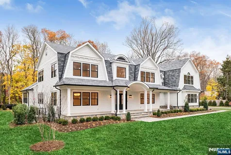 a front view of a house with a garden and trees