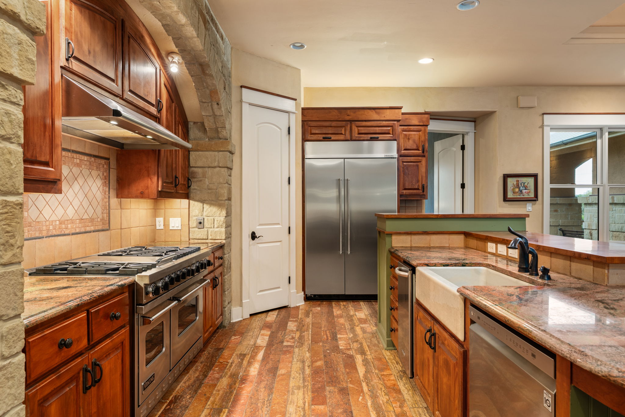 23426 Oscar Road Spicewood, TX 78669 - Photo 22 of 40 View of the kitchen showing the pantry door on the left and the door into the media room on the right.