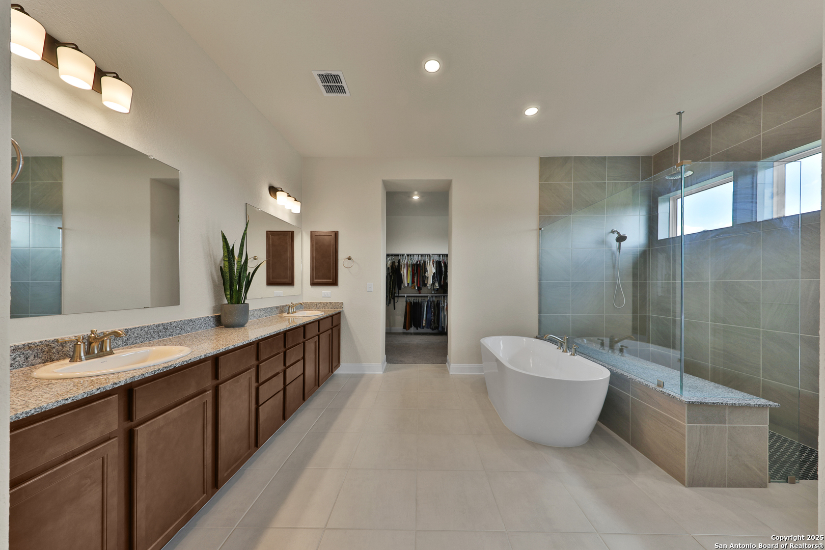 195 Piper Street Castroville, TX 78009 - Photo 33 of 47 a spacious bathroom with a double vanity sink a large mirror and a bathtub