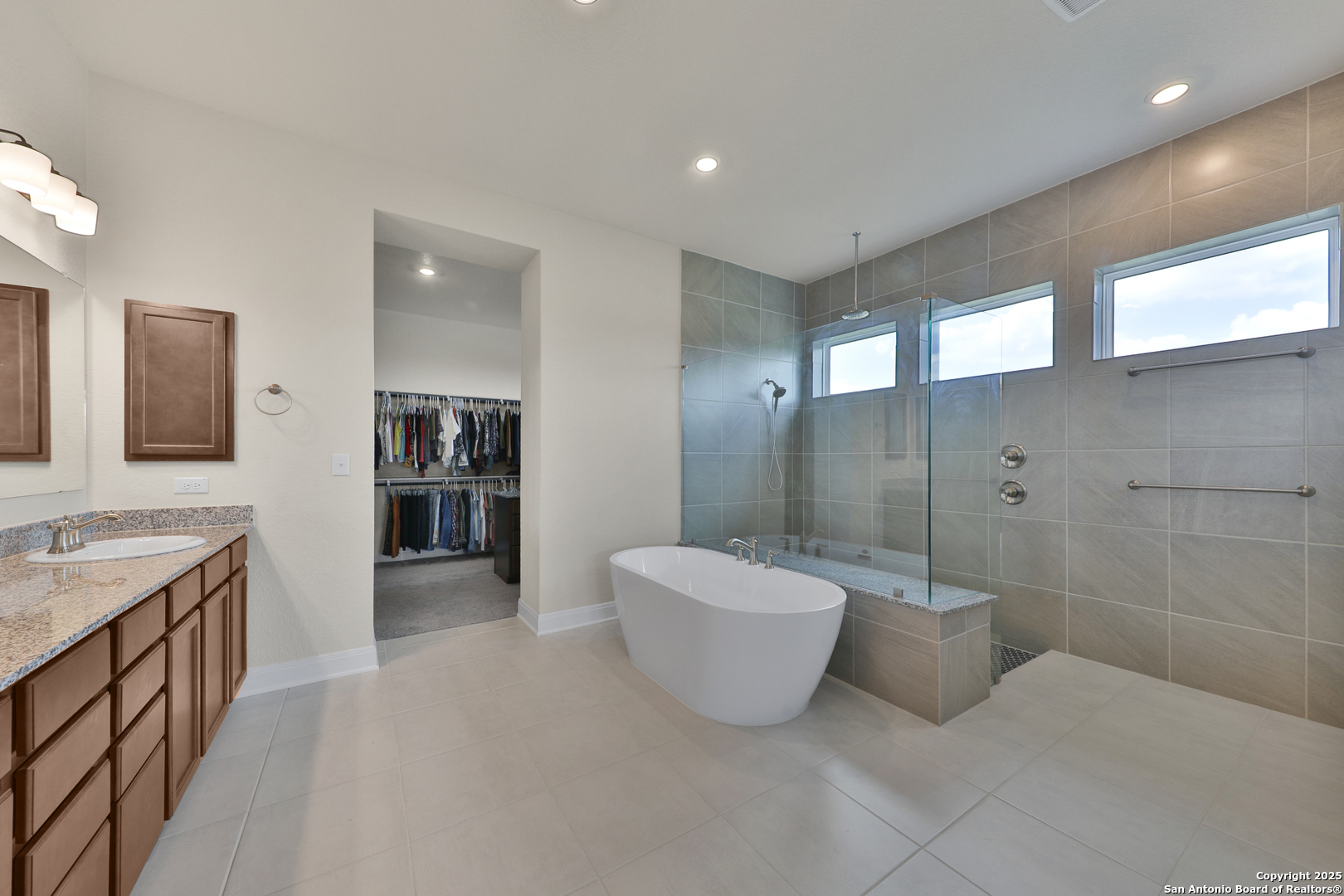 195 Piper Street Castroville, TX 78009 - Photo 36 of 47 a spacious bathroom with a double vanity sink a large mirror and a bathtub