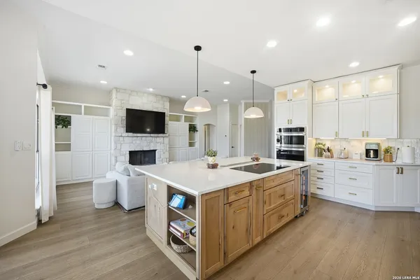 a large kitchen with kitchen island a stove a sink a center island and a wooden floor