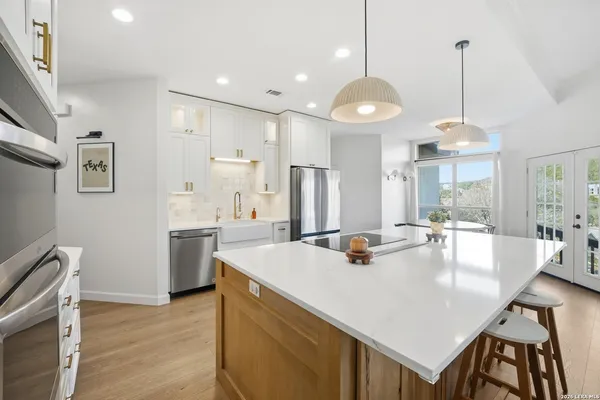 a kitchen with stainless steel appliances granite countertop a stove a refrigerator a kitchen island a dining table and chairs with wooden floor