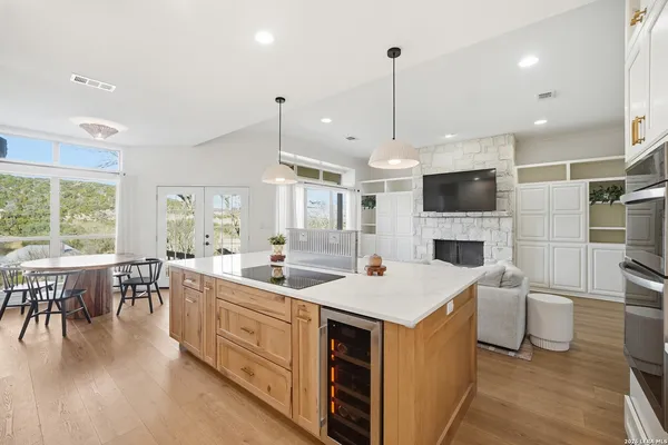 a open kitchen with stainless steel appliances granite countertop a stove top oven a sink dishwasher a dining table and chairs with wooden floor