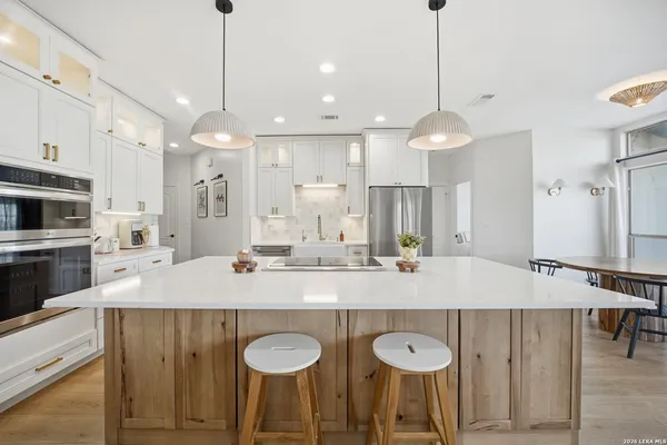 a large kitchen with granite countertop a stove a sink a center island a table and chairs