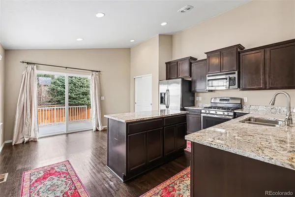 a kitchen with kitchen island granite countertop stainless steel appliances and wooden cabinets
