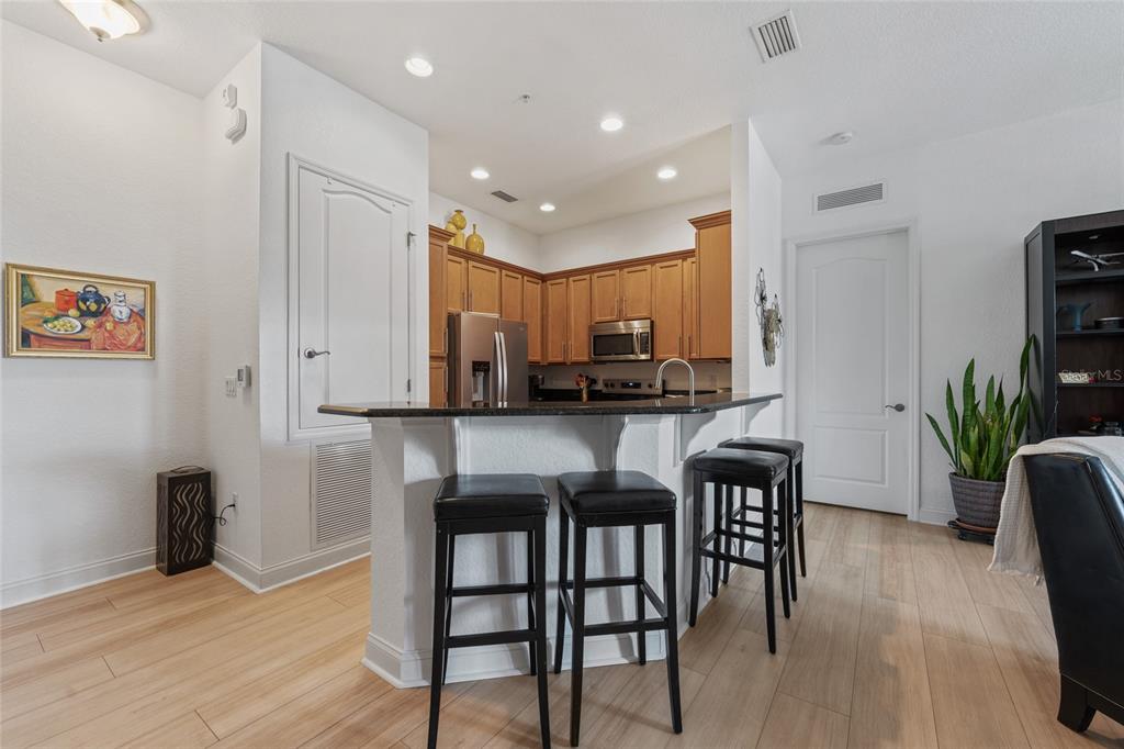 1819 Common Way Road, Unit 203 Orlando, FL 32814 - Photo 6 of 23 a kitchen with stainless steel appliances kitchen island granite countertop a dining table chairs and a refrigerator