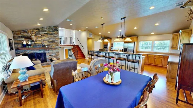 a kitchen with stainless steel appliances granite countertop a stove top oven a dining table and chairs with wooden floor