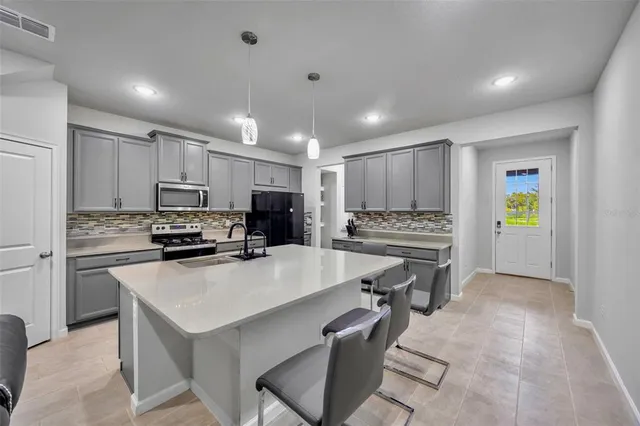 a kitchen that has a sink a refrigerator and a stove top oven with white cabinets