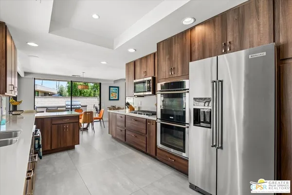 a kitchen with stainless steel appliances kitchen island granite countertop a sink dishwasher and a dining table with chairs