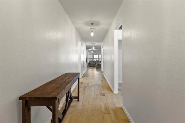 a hallway with wooden floor staircase and a bathroom