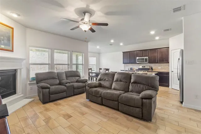 a living room with stainless steel appliances granite countertop couches a flat screen tv and kitchen view