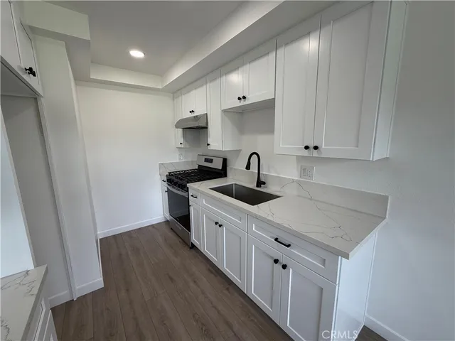 a kitchen with white cabinets sink and stove